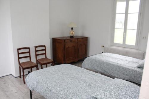 een slaapkamer met 2 bedden, een dressoir en 2 stoelen bij LE TILLEUL in Saint-Ouen-du-Tilleul