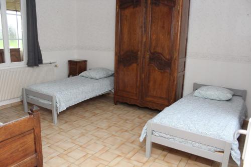Habitación con 2 camas y armario de madera. en LE TILLEUL, en Saint-Ouen-du-Tilleul