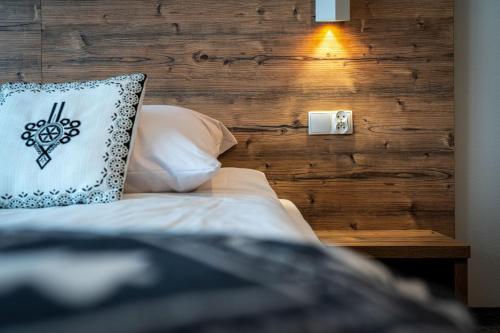 a bed with a pillow next to a wooden wall at Dom Wypoczynkowy u Niedzielskich in Białka Tatrzanska