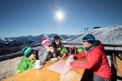 a group of people sitting at a table in the snow at Pension Bergheim in Reith im Alpbachtal
