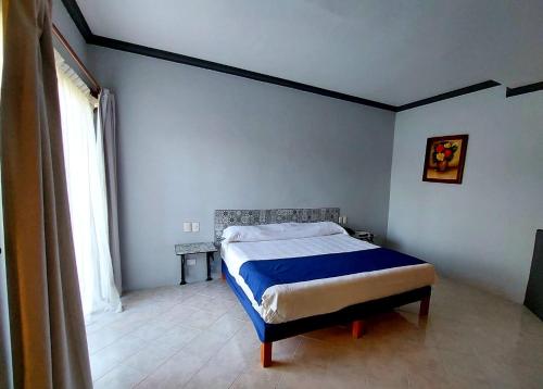 a bedroom with a bed with blue sheets and a window at Gran Hotel Hacienda De La Noria in Aguascalientes