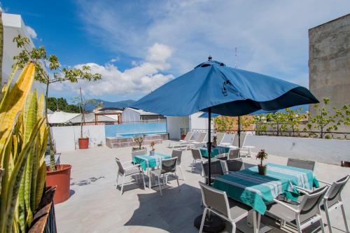 a patio with tables and chairs and a blue umbrella at Suites de La Parra in Oaxaca City