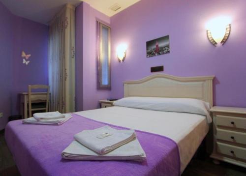 a purple bedroom with a bed with towels on it at Hostal Regio in Madrid