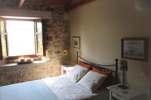 a bedroom with a bed and a window at Amygdalia, a Stone House in a quiet landscape in Leonidion