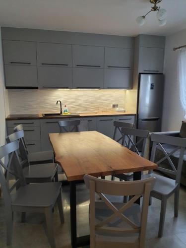 a kitchen with a wooden table and chairs and a refrigerator at Świerkowa Chata in Bałtów