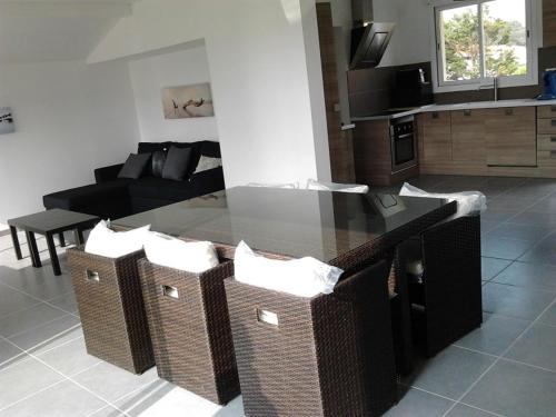 - un salon avec une table en verre et des chaises en osier dans l'établissement villa l atlantide, à Vieux-Boucau-les-Bains