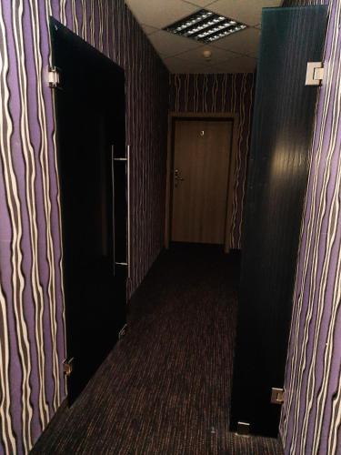 an empty hallway with a door and a room with purple walls at Hotel Arsenał in Gliwice