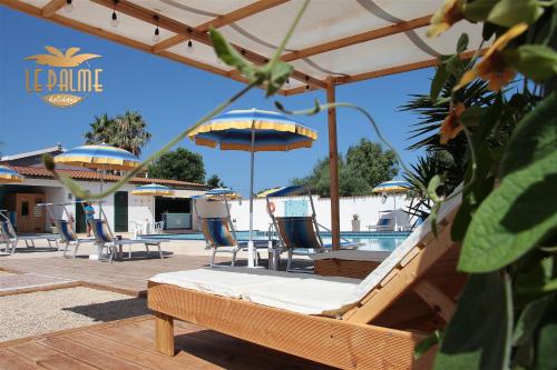 un patio con sillas y sombrillas junto a una piscina en Le Palme Holidays, en Palmadula