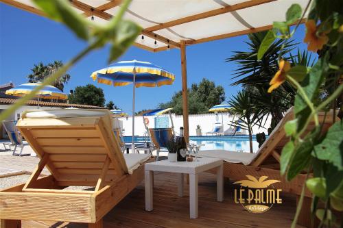 a patio with an umbrella and chairs and a pool at Le Palme Holidays in Palmadula