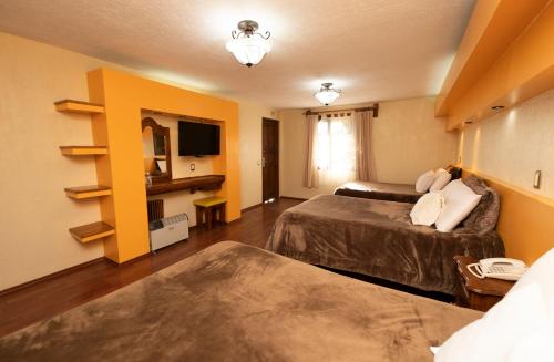 a hotel room with two beds and a television at Gran Hotel El Encanto in San Cristóbal de Las Casas