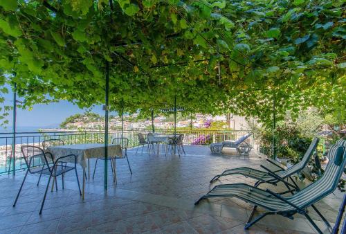 eine Terrasse mit Tischen und Stühlen unter einem Baum in der Unterkunft Apartments Tonci in Podgora