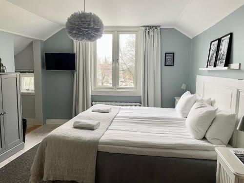 um quarto com uma grande cama branca e uma janela em Berglings Boutique Hotell em Norrtälje