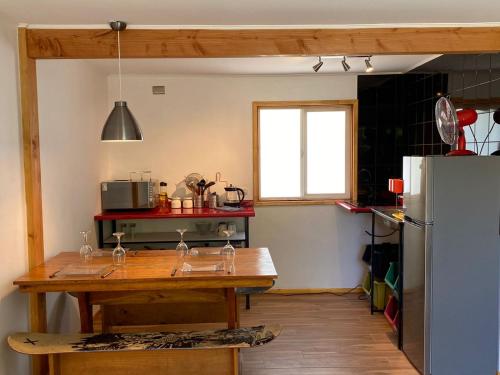 a kitchen with a wooden table and a refrigerator at French Andes Apart Hostel in Pucón