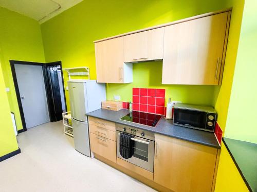 a kitchen with yellow and green walls and a microwave at PHOENIX Boutique Apartments in Goole