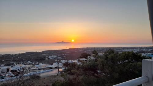 a sunset over a city with a mountain in the distance at Alonia Studios in Firostefani