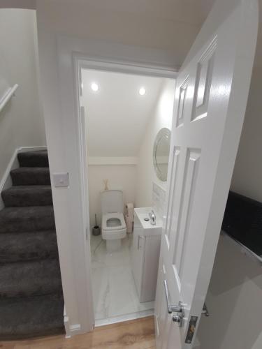 a white bathroom with a toilet and a staircase at Modern house close to Glasgow Green in Glasgow