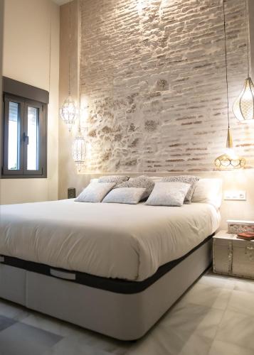 a bedroom with a large bed with a stone wall at innCádizPalacio Conde Casa-Brunet in Cádiz