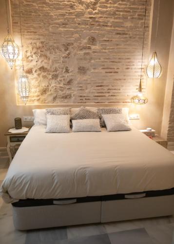 a bedroom with a large white bed with a stone wall at innCádizPalacio Conde Casa-Brunet in Cádiz
