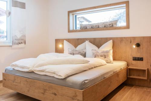 a bedroom with a large bed with a wooden headboard at Aparthaus Alpenzauber in Neustift im Stubaital
