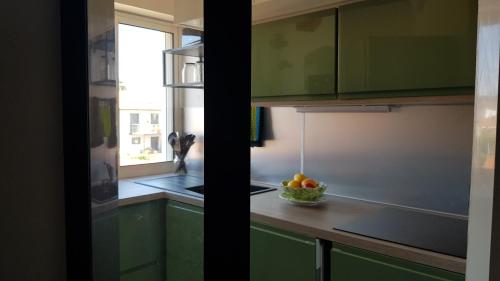 a kitchen with green cabinets and a bowl of fruit at ARCACHON PETIT PORT - T3 VUE BASSIN in Arcachon
