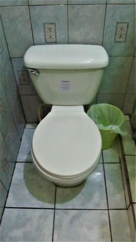a white toilet in a bathroom with a trash can at AC Room 4 Persons Hospedaje Don Wilfredo in San Juan del Sur
