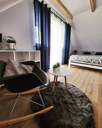 a living room with a black chair and a bed at Domki w Bieszczadach - Apartamenty in Hoczew