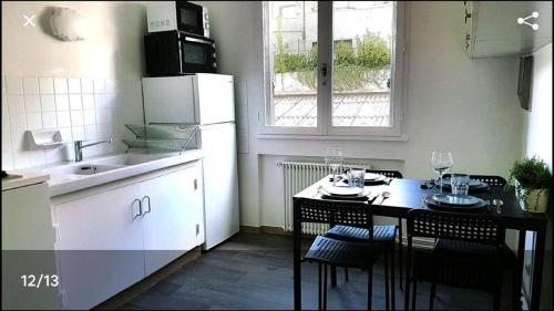 Il comprend une cuisine équipée d'une table avec des chaises et d'un réfrigérateur blanc. dans l'établissement GRAND STUDIO avec balcon -4 PERSONNES-DISNEYLAND- PARIS a 10 minutes, à Thorigny-sur-Marne