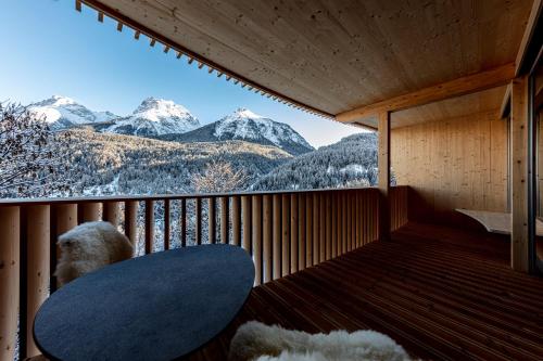 a room with a balcony with a view of mountains at Hotel Arnica Scuol - Adults Only in Scuol