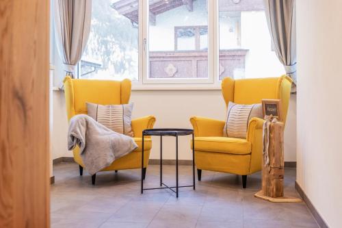 two yellow chairs and a table in front of a window at Aparthaus Alpenzauber in Neustift im Stubaital