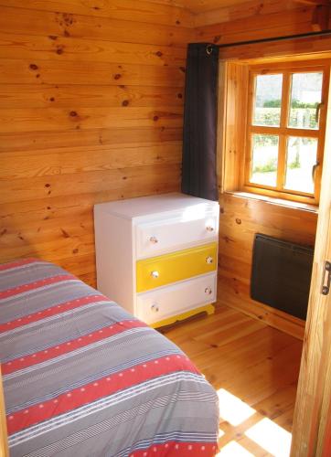 une chambre avec un lit, une commode et une fenêtre dans l'établissement bord de mer, chalet en bois avec tandem, à Lion-sur-Mer