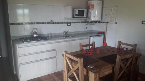 a kitchen with a table and a sink and a stove at Departamento Teodelina in Quehué