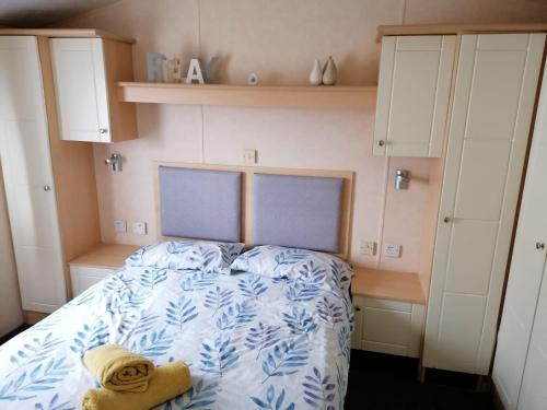 a bedroom with a bed with a blue and white comforter at 2 Bed Static Caravan @ Hoburne Devon Bay in Paignton