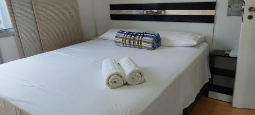 Una cama blanca con dos toallas y una bolsa. en Apartamento Familiar 3 quartos - Leblon en Río de Janeiro