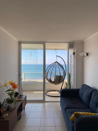 a living room with a blue couch and a view of the ocean at Departamento frente al mar full equipado in Coquimbo