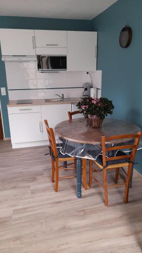 - une cuisine avec une table, deux chaises et une table fleurie dans l'établissement Aux doux refuges de la muse Studio, à Montjaux