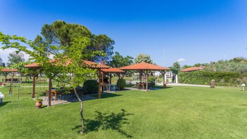 a green yard with tables and umbrellas in a park at Studios Anna in Vourvourou