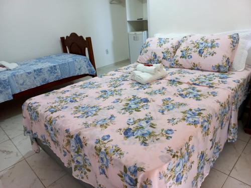 a bedroom with a bed with a floral bedspread at Pousada Recanto das Oliveiras-Búzios in Búzios