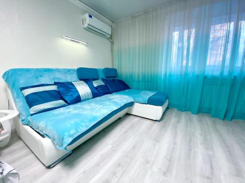 Schlafzimmer mit blauem Bett und blauen Vorhängen in der Unterkunft Апартаменти завжди зі світлом in Dnipro