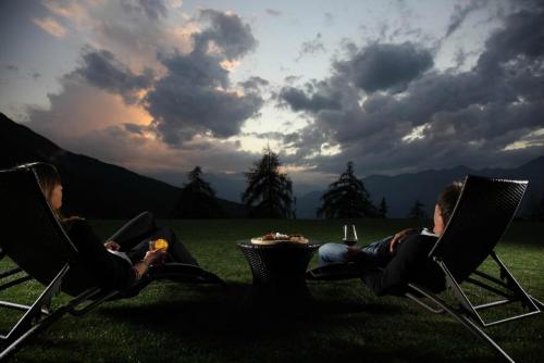two people sitting in chairs in a field with food at Hotel La Chance in Pila