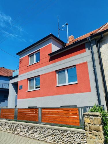 a red and white house with a wooden fence at Apartmány na Zahradní in Břeclav