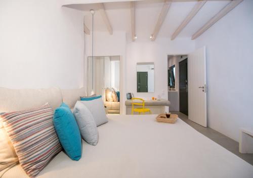 a white room with a large bed with blue pillows at Princess Of Naxos in Naxos Chora