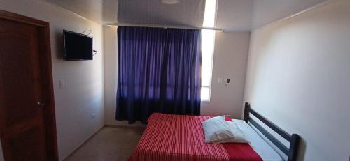 a bedroom with a bed with a red blanket and a window at Hotel Alta Vista Campestre in Tibasosa