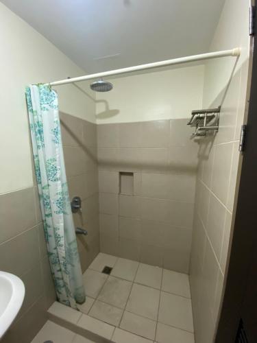 a bathroom with a shower curtain and a sink at Rosarich Homestay - Bristle Ridge Residences in Baguio