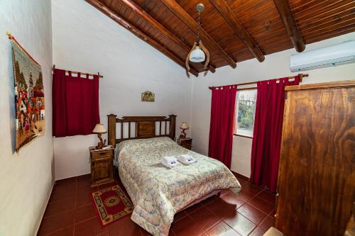 a bedroom with a bed with red curtains and a window at Cabanas Villa Santa Clara del Atuel in San Rafael