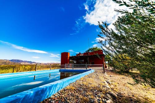 a swimming pool in front of a red building at Cabanas Villa Santa Clara del Atuel in San Rafael