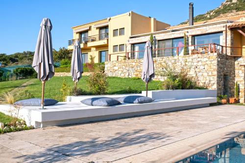 a bed in front of a house with umbrellas at Ferenity in Iraklitsa