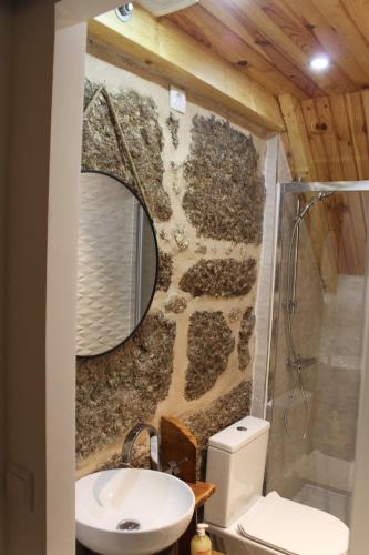 a bathroom with a stone wall and a mirror at Casas Puro Granito in Sabugueiro