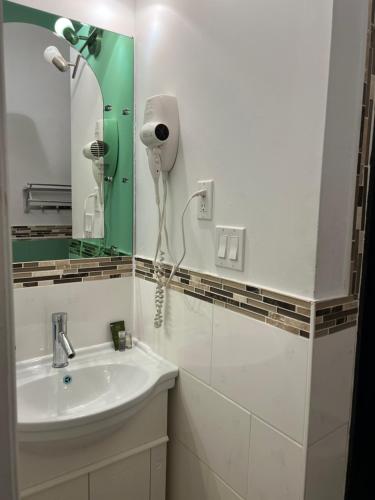 a bathroom with a sink and a hair dryer on the wall at Adas Guesthouse in Toronto