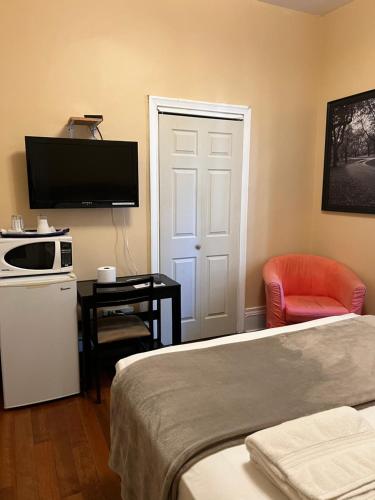una camera d'albergo con letto, TV e sedia di Adas Guesthouse a Toronto