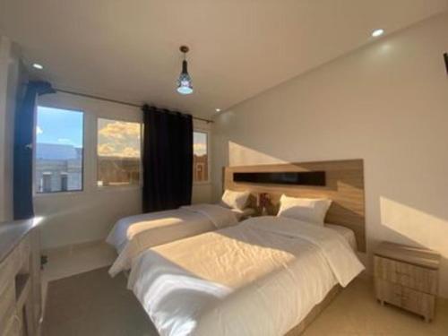 1 dormitorio con 2 camas y ventana en HOTEL NOON, en Laayoune
